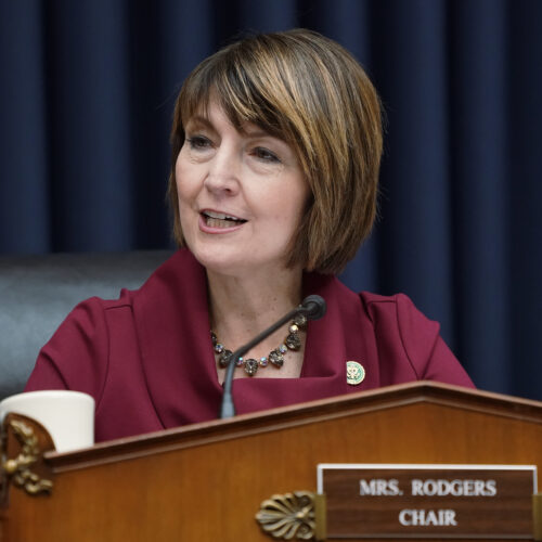 Cathy McMorris Rodgers sits behind a brown podium before a blue curtain in a maroon jacket in Washington D.C.