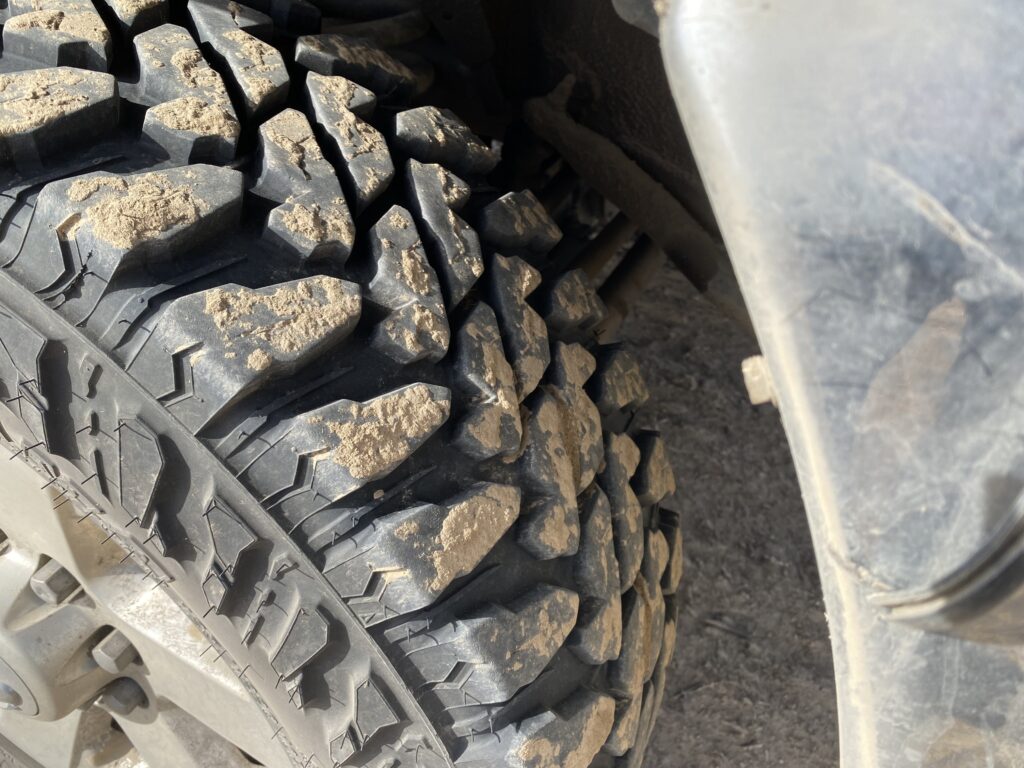 A truck tire with buff-colored dust on the tread.