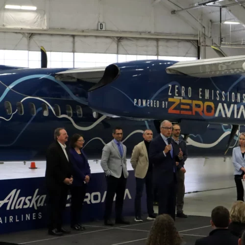Tom Banse / NW News Network Elected officials and corporate leaders gathered in a Paine Field hangar to celebrate the handover of a retired Alaska Airlines Q400 turboprop, which will be converted to hydrogen-electric propulsion over the next year