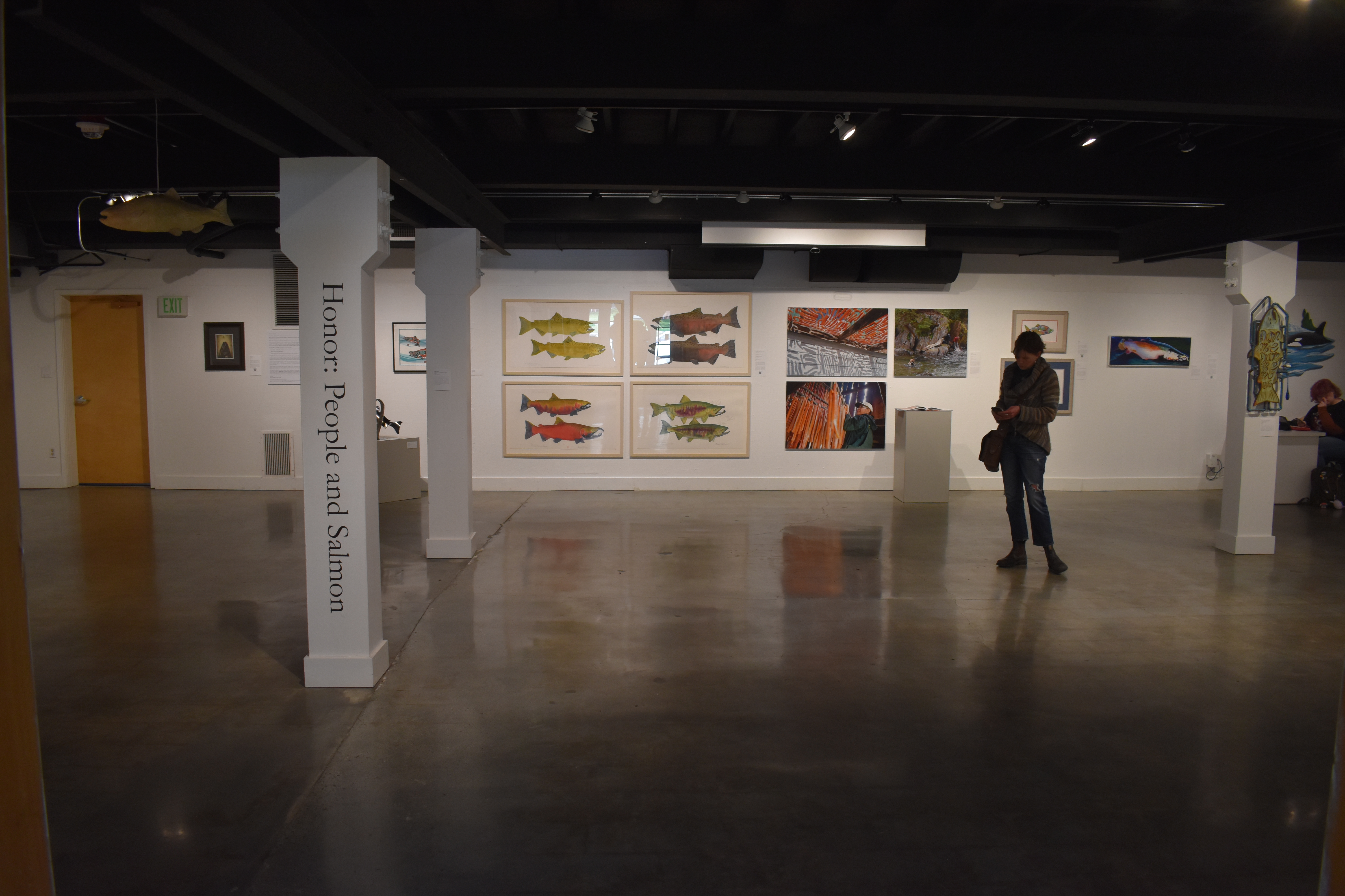 Both Eileen Klatt and Amy Gulick's art can be seen here, from the Honor: People and Salmon exhibit. Britt Freda stands in the gallery space. Some of the artwork, including Klatt and Gulick's work, is on display at the Seattle Patagonia store. Photo by Lauren Gallup.