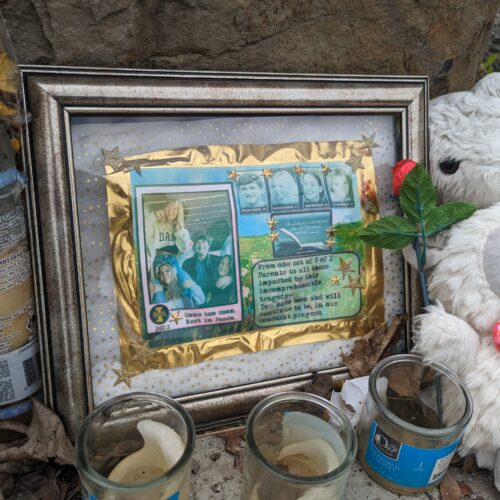 Candles, stuffed toy lambs and a framed photo of the four students sits atop grey rocks in front of the King Road house.