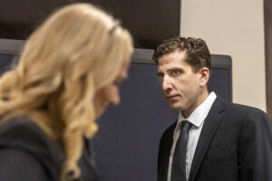 Bryan Kohberger walks toward his attorney Anne Taylor in a black suit jacket, black tie and white shirt.