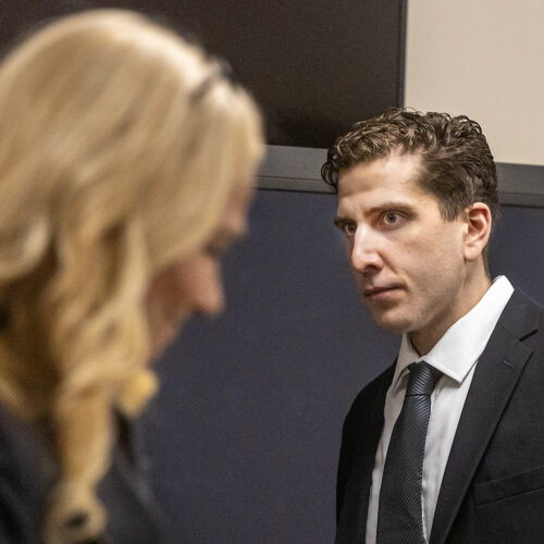 Bryan Kohberger walks toward his attorney Anne Taylor in a black suit jacket, black tie and white shirt.