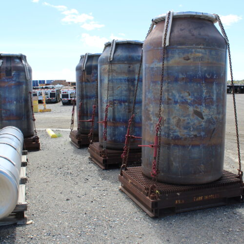 Several low-activity waste containers sit at Hanford, while one high-level waste canister lays in the foreground