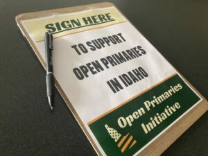 A clipboard reads "sign here to support open primaries in Idaho" in green lettering.