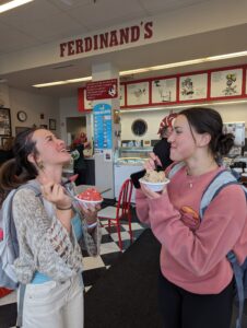 Two college students with backpacks on eat cups of ice cream at the Ferdinand's ice cream shoppe.