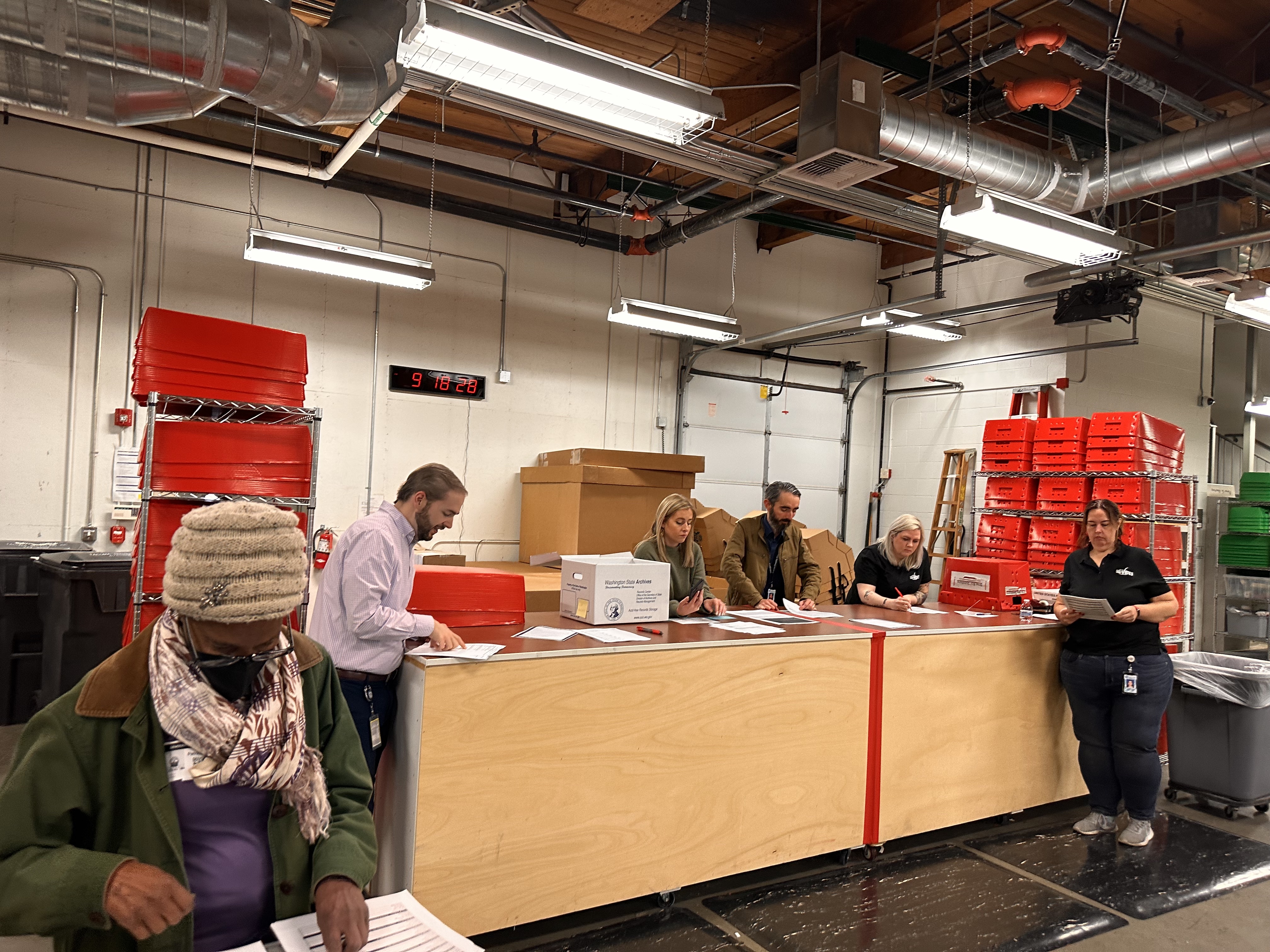 As Kyle Haugh reads out the results of the test ballots, county staff and observers compare to the predetermined results. (Credit: Lauren Gallup / NWPB)