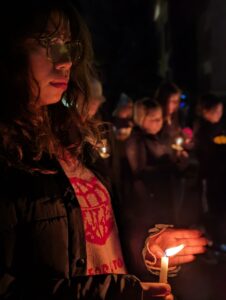 A woman with glasses holds a light as she looks toward the stage on the University of Idaho campus.