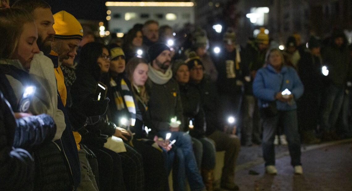 People hold lights while standing at a vigil in Boise, Idaho on November 23, 2022. Many of them are wearing black.