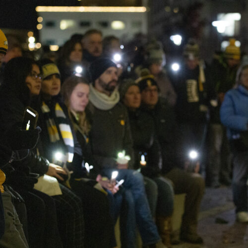 People hold lights while standing at a vigil in Boise, Idaho on November 23, 2022. Many of them are wearing black.