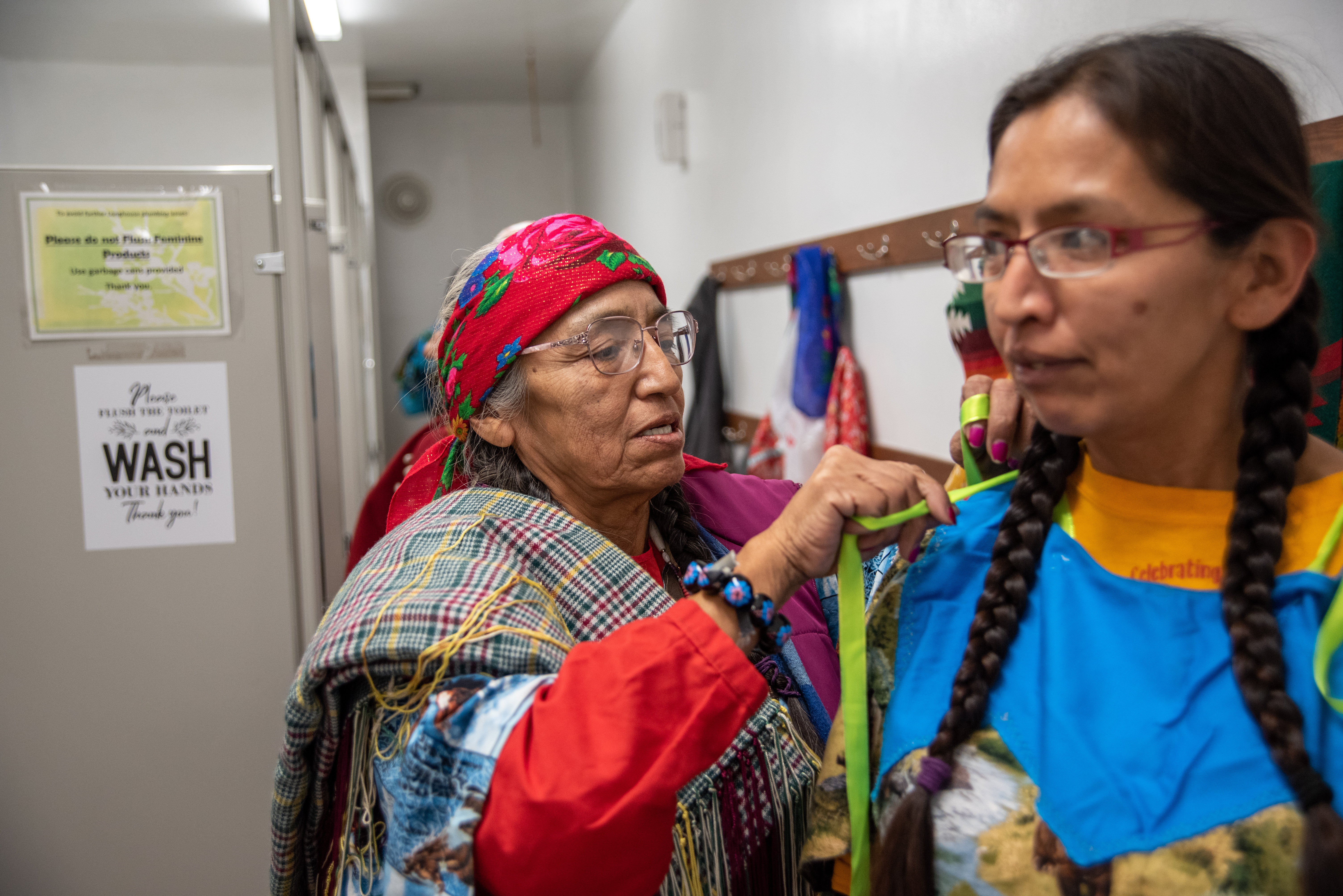 Cindy Yallup, left, ties the ribbons of daughter Norma Patrick’s wing dress as the women prepare for Indian New Year at the longhouse in Mission, Ore., on Dec. 21. They were visiting from the Yakama reservation and said they enjoyed seeing family and hearing the singing and the laughter in the kitchen