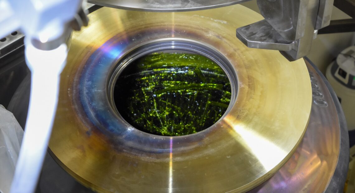 The poured glass appears emerald green, just before it’s lidded and transported to an export bay at Hanford in southeast Washington. Hanford officials are celebrating this first container of glass to be poured from the Waste Treatment Plant at the radioactive cleanup site. (Courtesy: Bechtel)