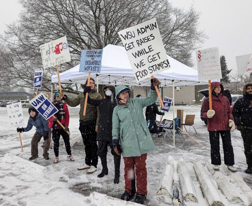 Students hold handmade signs under white tents on the Mt. Vernon Research and Extension Center. 