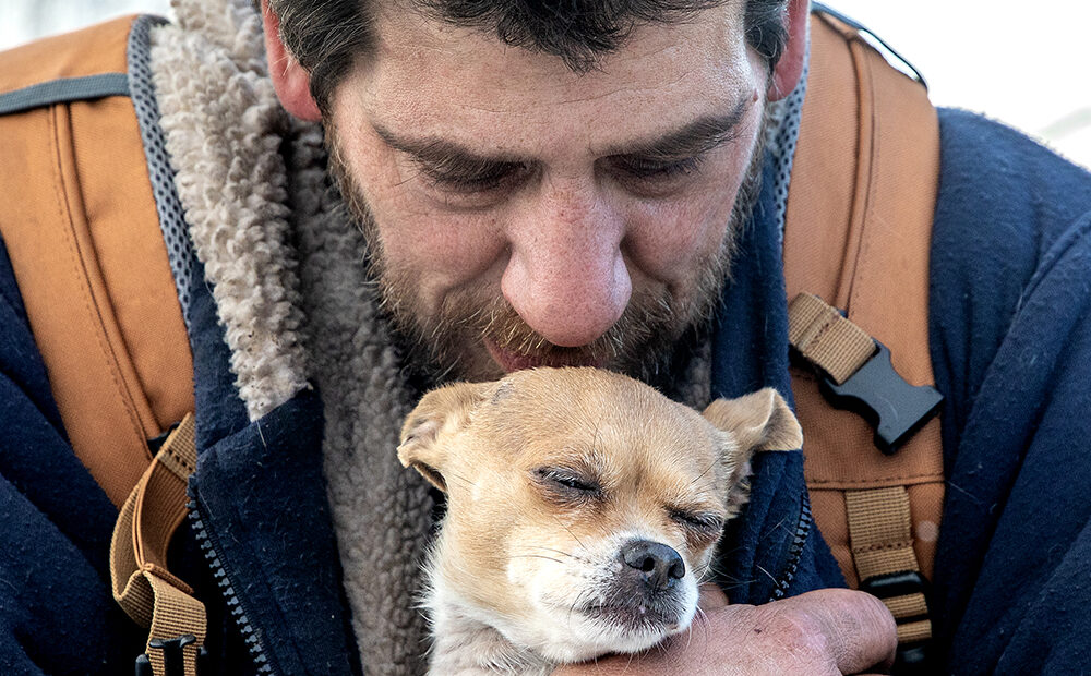 A man holds a dog close to his chest
