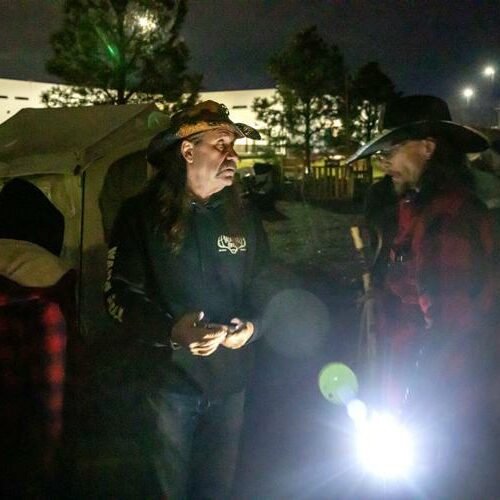 Cory James (left) talks with John "Cowboy" Parke as the remaining unhoused residents pack up their belongings at the homeless camp in Clarkston Monday evening. (Credit: August Frank / the Lewiston Tribune)