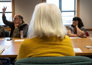 One participant, David Fox, raises his hand to share at the Port Angeles Senior and Community Center political discussion group. (Credit: Tela Moss / NWPB)