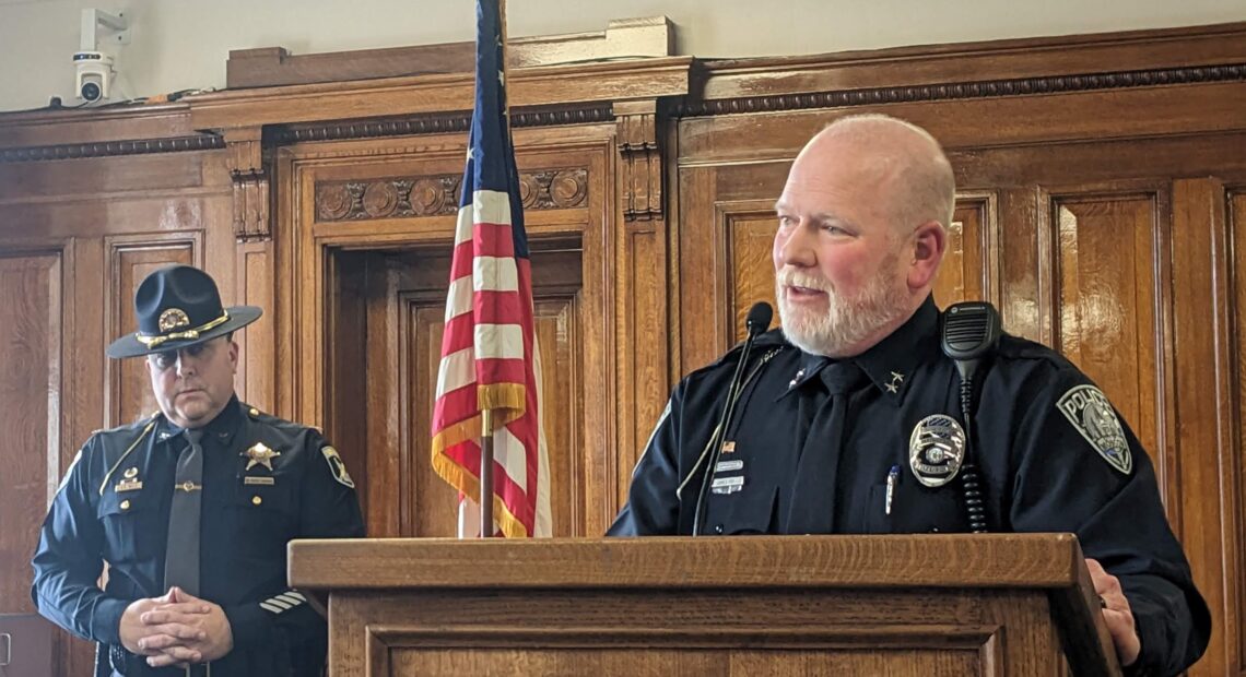 Police Chief James Fry stands at a wooden podium in uniform.