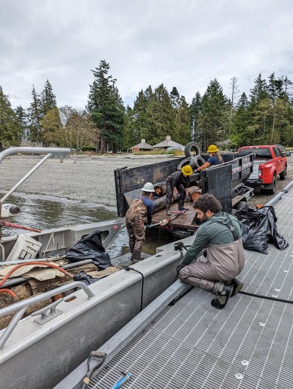 People load the debris onto a boat to haul it away to a sealed landfill for disposal. (Credit: Samish Indian Nation Department of Natural Resources)