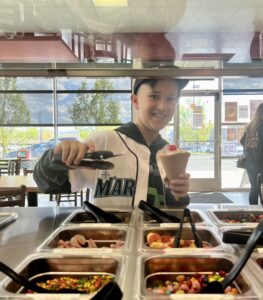 Nine-year-old Asher Niles, of Yakima, grabs frozen yogurt toppings after he competed on MasterChef Junior. The day before, Asher threw out the first pitch at a Seattle Mariner's game and is sporting a custom jersey the team made him. (Credit: Courtney Flatt)