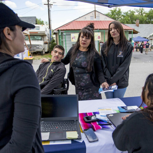 Maria Garibay, center, asks Anabella Cardoso, far left, with Esperanza, about social services and health care, while at CAFÉ's Pachanga & Mercadito resource fair with her son, Martin, and daughter, Yadhira, Saturday in Wenatchee. (Credit: Loren Benoit / Wenatchee World)